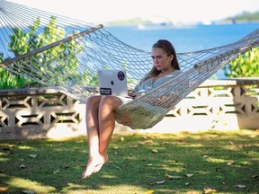 A woman working on a laptop on a hammock in Bermuda.