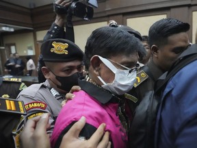 Former Indonesian Communication and Information Minister Johnny G. Plate, center, is escorted by prosecutors and police after his trial at an anti-graft court in Jakarta, Indonesia, Tuesday, June 27, 2023. Indonesia's anti-graft court on Tuesday began a trial for Plate who was charged with corruption over the construction of mobile phone transmission towers in remote parts of the country.