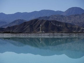 FILE - Mountains and a liming facility are reflected in a brine evaporation pond at Albemarle Corp.'s Silver Peak lithium facility, on Oct. 6, 2022, in Silver Peak, Nev. Threatened by possible shortages of lithium for electric car batteries, automakers are racing to lock in supplies of the once-obscure "white gold" in a politically and environmentally fraught competition from China to Nevada to Chile.