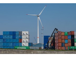A wind turbine near containers stacked at the newly merged Port of Antwerp-Bruges in Antwerp, Belgium, on Thursday, April 28, 2022. The port, unified today from the ports of Antwerp and Zeebrugge, is Europe's largest export port, throughput port for vehicles and integrated chemical cluster as well as one of the region's leading container ports, according to the port's website. Photographer: Nathan Laine/Bloomberg