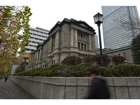 Pedestrians walk past the Bank of Japan (BOJ) headquarters in Tokyo, Japan, on Thursday, Dec. 19, 2019. The BOJ left policy untouched Thursday as a government stimulus package, progress in U.S.-China trade talks and signs of a bottoming of the global slowdown brightened the economic outlook.
