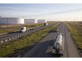 Trucks pass crude oil storage tanks outside Midland, Texas. Photographer: Matthew Busch/Bloomberg