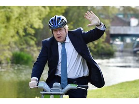 STOURBRIDGE, ENGLAND - MAY 05: British Prime Minister Boris Johnson waves as he rides a bike ride along the towpath of the Stourbridge canal in the West Midlands during a Conservative party local election visit on May 5, 2021 in Stourbridge, England. Political party leaders out campaigning on the final day before voters go to the polls to vote in local elections on Thursday, May 6.