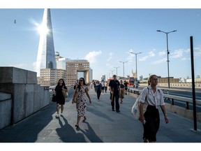 City workers cross London bridge in the morning during a heat wave in London on Monday, July 18, 2022.