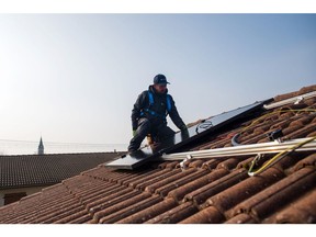An engineer fixes a DualSun SAS hybrid solar panel (PVT) onto the roof of a home during a residential installation in Saint Denis en Bugey, France, on Friday, March 3, 2023. Solar installations across Europe increased by a record 40-gigawatts last year, up 35% compared with 2021, in a jump was driven primarily by consumers who saw solar panels as a way to cut their own energy bills.