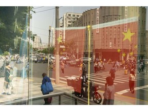 Chinese flags and pedestrians reflected in a window in Shanghai, China, on Friday, June 2, 2023. Chinese stocks staged a sharp rebound as optimism that the Federal Reserve will pause interest-rate hikes in June helped rekindle risk sentiment. Photographer: Raul Ariano/Bloomberg