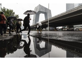 Pedestrians carry umbrellas near the CCTV headquarters building in Beijing, China, on Tuesday, July 4, 2023. Beijing has rolled out a raft of measures to prop up the economy, including asking big banks to lower their deposit rates at least twice in less than a year to boost lending, squeezing their margins. Photographer: Qilai Shen/Bloomberg