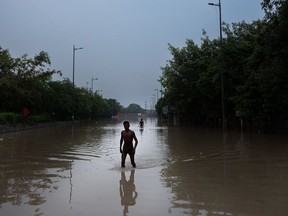 Residents wade through the flood waters in New Delhi on July 14. Photographer: Anindito Mukherjee/Bloomberg