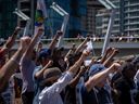 Striking port workers from the International Longshore and Warehouse Union Canada hold up their fists while attending a rally in Vancouver, on Sunday, July 9, 2023. 