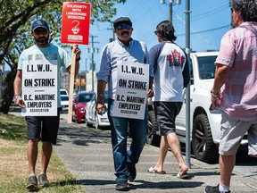 Striking port workers belonging to the International Longshore and Warehouse Union Canada walk the picket line near the Port of Vancouver’s entrance in Vancouver. Workers walked out at 8 a.m. Saturday.
