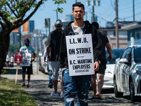 Striking port workers belonging to the International Longshore and Warehouse Union Canada walk the picket line near the Port of Vancouver’s entrance in Vancouver.