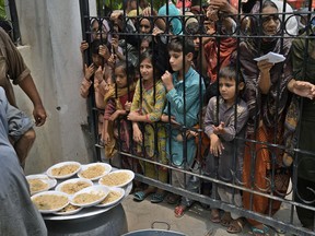 Women and children wait for free food at a distribution point in Lahore, Pakistan, on Tuesday, June. 27, 2023.