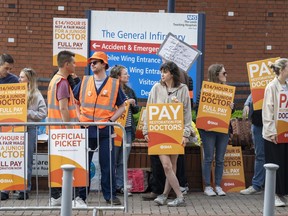 FILE - Junior doctor and members of the British Medical Association (BMA) stand on the picket line outside Leeds General Infirmary at the start a five-day strike amid the continuing dispute over pay, the longest walkout of its kind in the history of the NHS, in Leeds, England, on July 13, 2023. Tens of thousands of doctors in Britain's state-funded health service will go on strike for a further four days in August as their pay dispute with the government shows few, if any, signs of resolution, their union said Wednesday July 26, 2023.