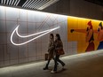 Women walk by a Nike store in Beijing, China.