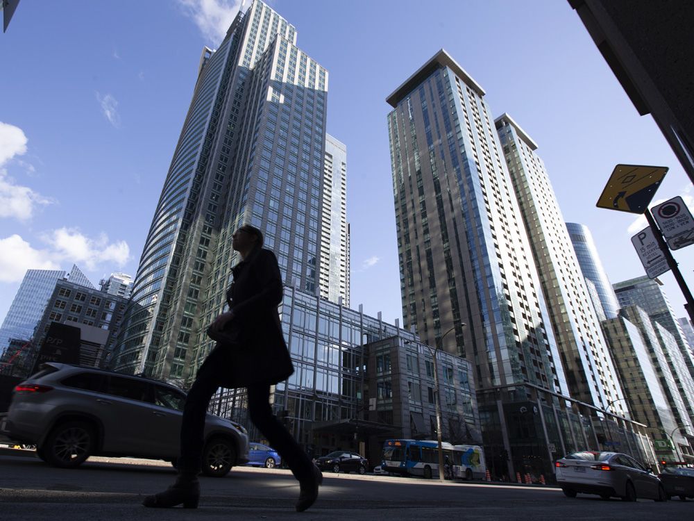 A pedestrian walking past office buildings in Montreal.
