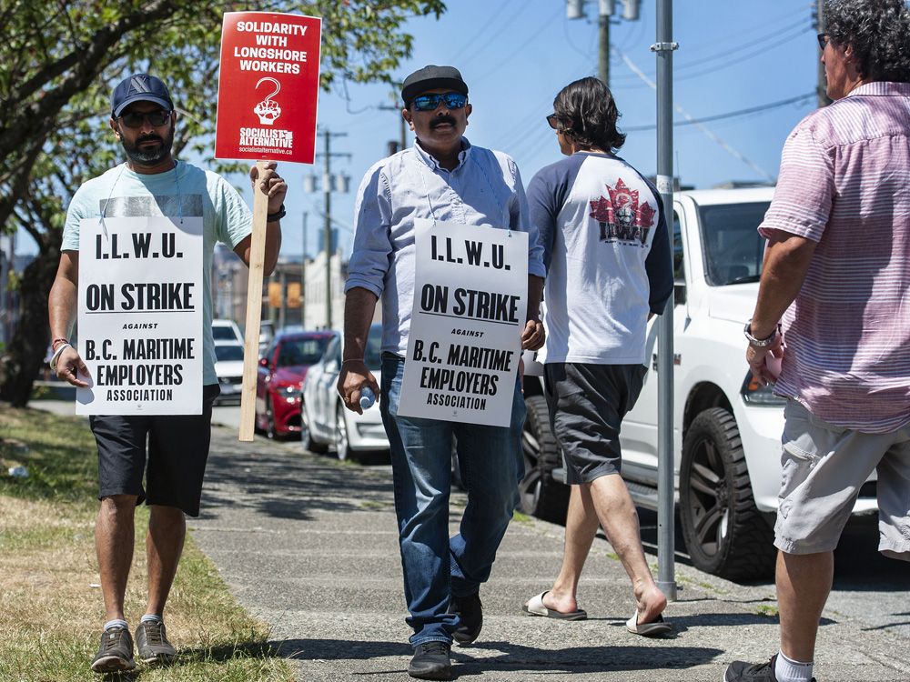Striking port workers belonging to the International Longshore and Warehouse Union Canada walk the picket line near the Port of Vancouver&rsquo;s Clark Drive entrance.