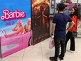 Moviegoers stand in front of "Barbie" and "Oppenheimer" posters at a Cineplex Inc. theatre in Islamabad.
