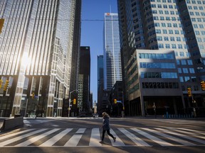A woman crosses the street during morning commuting hours in the Financial District of Toronto.