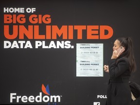 A pedestrian walking past Freedom Mobile advertising in Toronto.