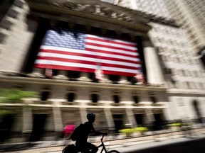 A person bikes past the New York Stock Exchange on Wednesday, June 29, 2022 in New York. Stocks shifted between gains and losses on Wall Street Wednesday, keeping the market on track for its fourth monthly loss this year.