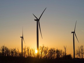 Wind turbines spin in front of the setting sun