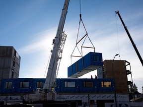 A prefabricated apartment is lifted onto housing under construction in Edmonton.