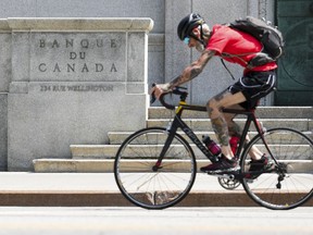 A cyclist makes their way past the Bank of Canada in Ottawa on Tuesday, July 11, 2023.&ampnbsp;The Bank of Canada says it's trying to not raise interest rates more than it has to, as members of the governing council are mindful of the risks associated with raising rates too much. THE&ampnbsp;CANADIAN PRESS/Sean Kilpatrick