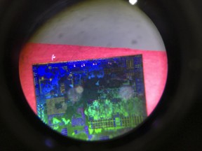 FILE - A Chinese microchip is seen through a microscope set up at the booth for the state-controlled Tsinghua Unigroup project which is aimed at driving China's semiconductor ambitions during the 21st China Beijing International High-tech Expo in Beijing, China, on May 17, 2018. China has imposed export curbs on two metals used in computer chips and solar cells, expanding a squabble with Washington over high-tech trade ahead of Treasury Secretary Janet Yellen's visit to Beijing this week.