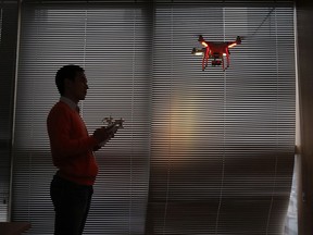 FILE - A staff member from DJI Technology Co. demonstrates the remote flying with his Phantom 2 Vision+ drone inside his office in Shenzhen, south China's Guangdong province, on Dec. 15, 2014. China imposed restrictions Monday, July 31, 2023 on exports of long-range civilian drones, citing Russia's war in Ukraine and concern that drones might be converted to military use.