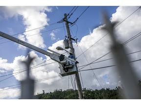 A worker fixing power lines on a utility pole in the town of Limones.  Photographer: Xavier Garcia/Bloomberg