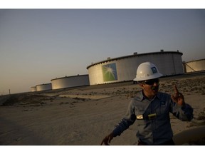 An employee walks past crude oil storage tanks at the Juaymah Tank Farm in Saudi Aramco's Ras Tanura oil refinery and oil terminal in Ras Tanura, Saudi Arabia, on Monday, Oct. 1, 2018. Saudi Arabia is seeking to transform its crude-dependent economy by developing new industries, and is pushing into petrochemicals as a way to earn more from its energy deposits.