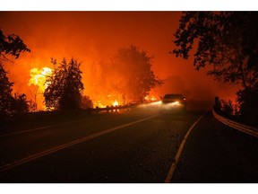 An automobile passes along Highway 128, east of Lake Berryessa, as flames burn surrounding trees and fauna during the Hennessey fire in Napa County, California, U.S., on Tuesday, Aug. 18, 2020. More Northern Californians were chased out of their homes Tuesday by lightning-sparked wildfires that burned out of control in several counties amid a punishing heat wave that pushed temperatures into the triple digits, according to the San Francisco Chronicle.