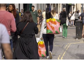 A shopper carries Next Plc bags on Oxford Street in London, UK, on Thursday, May 25, 2023. UK retailers saw sales jump more than expected last month, recovering from heavy rain that kept people home the month before.