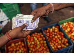A customer hands rupee banknotes to a vendor at a wholesale vegetable market in Ahmedabad, India, on Wednesday, July 19, 2023. A spike in inflation in June justifies the decision of Indian policymakers to maintain higher rates for longer, the country's central bank said in a report.