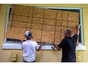 Residents place a wooden board to protect a house in St. Petersburg, Florida, US, on Monday, Aug. 28, 2023. Tropical Storm Idalia strengthened near Cuba as it moves toward Florida's west coast, threatening to strike as a major hurricane Wednesday with life-threatening rains and storm surge.
