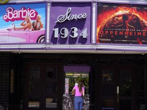 A patron buys a movie ticket underneath a marquee featuring the films "Barbie" and "Oppenheimer" at the Los Feliz Theatre, Friday, July 28, 2023, in Los Angeles.