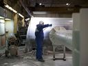 Un trabajador recubriendo con polvo una columna en las instalaciones de Automatic Coating Ltd.  en Toronto.
