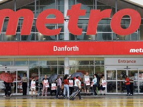 Customers, workers and security stand outside a Metro grocery store in Toronto.