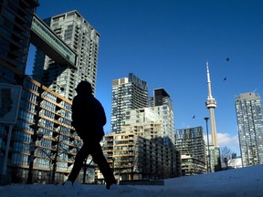 A pedestrian passes by condo towers in Toronto.