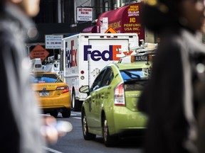 A FedEx Corp. vehicle sits parked as taxi cabs drive past in the Midtown neighbourhood of New York.