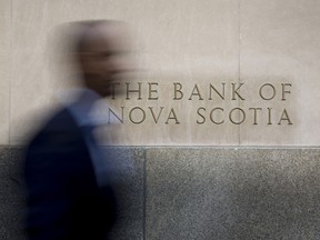 A commuter walks past signage displayed on the Bank of Nova Scotia in the financial district of Toronto.