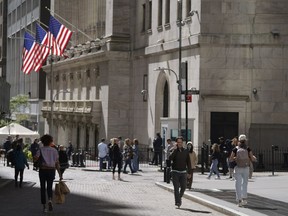 FILE - Visitors to the financial district walk past the New York Stock Exchange, Friday, Sept. 23, 2022, in New York.