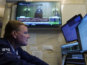 Trader John Bowers works on the floor of the New York Stock Exchange, Friday, Aug. 25, 2023, as Federal Reserve Chair Jerome Powell's speech shows on a television screen. Stocks are holding on to gains after Powell said more rate hikes could be on the way to continue the Fed's fight against inflation.