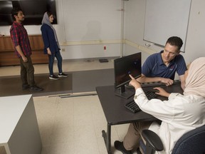 University of New Brunswick professor Erik Scheme, second from right, is shown in his lab at UNB where they use pressure-sensitive floor tiles to analyze people's gait in Fredericton, New Brunswick on Friday August 4, 2023. Here Scheme and Mayssa Rekik, Mitacs Globalink Intern from Tunisia, right, analyze the footsteps of Arijit Samal, Mitacs Globalink Intern from India, left, and Ala Salehi, graduate student.