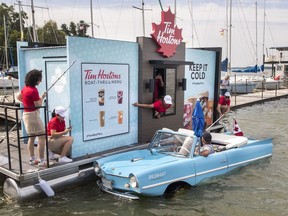 Restaurant Brands International Inc. is reporting double-digit sales growth amid higher revenues at Tim Hortons and Burger King. Rick Lloyd, from Pickering, with wife Susan and son Chris, take their amphibious car to the Tim Horton's boat drive through on Lake Scugog near Port Perry, Ontario, August 5, 2023.