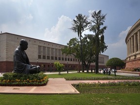 FILE - A statue of Mahatma Gandhi sits between the old and new Parliament House buildings on the opening day of the monsoon session of the Indian parliament, in New Delhi, India, Thursday, July 20, 2023. Indian lawmakers have approved a data protection legislation that seeks to better regulate big tech firms and penalize companies for data breaches. The Digital Personal Data Protection bill was passed by the upper house of Parliament Wednesday amid concerns by opposition parties and digital experts who said it undermines the privacy rights of Indians.