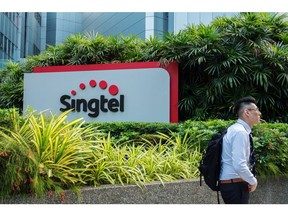 A man walks past signage for Singapore Telecommunications Ltd. (Singtel) in Singapore, on Friday, July 6, 2018. Singtel, Southeast Asia's largest telecom services provider, will start a regional competitive gaming league as part of its diversification into e-sports and digital content. Photographer: Nicky Loh/Bloomberg