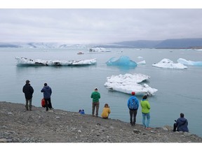 HOF, ICELAND - AUGUST 15: Tourists look at icebergs that have broken off of receding Breidamerkurjokull glacier, which looms behind, at Jokulsarlon lake on August 15, 2021 near Hof, Iceland. Breidamerkurjokull, among the biggest of the dozens of glaciers that descend from Vatnajokull ice cap, is melting, losing an average of 100 to 300 meters in length annually. Breidamerkurjokull's meltwater has created Jokulsarlon, which is now Iceland's biggest lake. Iceland is undergoing a strong impact from global warming. Since the 1990s, 90 percent of Iceland's glaciers have been retreating and projections for the future show a continued and strong reduction in size of its five ice caps.