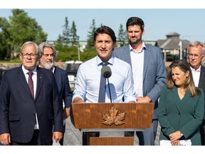 Canadian Housing Minister Sean Fraser stands behind Prime Minister Justin Trudeau during a news conference in Prince Edward Island in August.