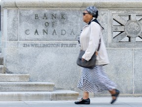 A woman walks past the Bank of Canada building in Ottawa. Interest rate cuts are expected in the second half of 2024, Desjardins economists say.